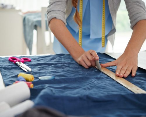 Hands of tailor drawing on fabric before sewing